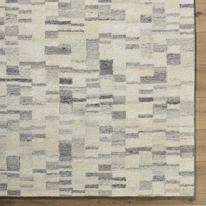 Close-up of the Max Handmade Becki Owens x LIVABLISS rug. Wool rug features a contemporary geometric block pattern in ivory, gray, and charcoal. Corner