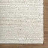 Close up of the beige, hand woven, textured Clayne Premium Wool Area Rug. Corner