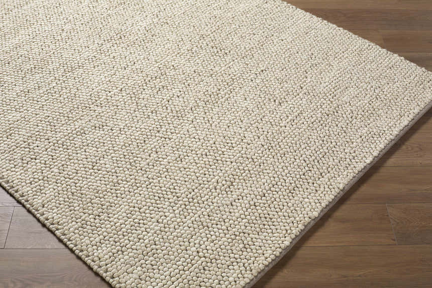 Close-up of the textured Clayne Dark Beige wool area rug, showing its hand-woven construction and medium brown color. Corner