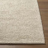 Close-up of the hand-woven Clayne Dark Beige wool area rug, showing its looped texture and medium brown color on wood floor. Front