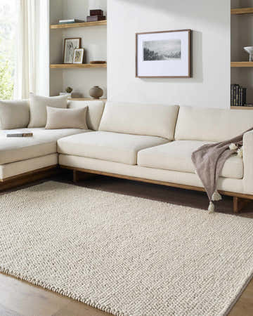 Living room with a Clayne Dark Beige wool rug, a sectional sofa, and light wood accents. Roomscene-Rectangle
