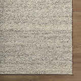 Close-up of the hand woven Clayne Beige & Charcoal Premium Wool Area Rug showing its textured, looped wool design. Corner