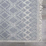 Close-up of Ramsbury Denim Blue Wool Rug showing geometric pattern, fringe, and textured weave. Swatch