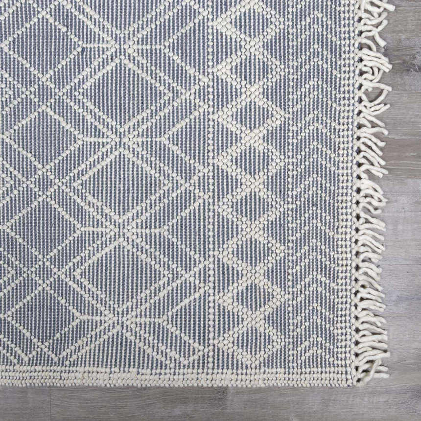 Close-up of Ramsbury Denim Blue Wool Rug showing geometric pattern, fringe, and textured weave. Swatch