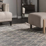 Living room scene with a Ramsbury Denim Blue Wool Rug, beige armchair, and ottoman. Geometric pattern. Roomscene-Rectangle