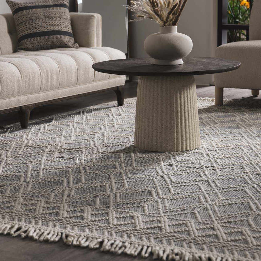 Living room scene with a Ramsbury Denim Blue Wool Rug, beige sofa, and round coffee table with a vase. Roomscene-Rectangle