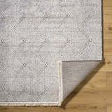 Close-up of Cannan Area Rug, ivory and black geometric design, machine woven texture, fringe detail. Fold