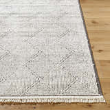 Close-up of Cannan Area Rug in black and ivory, featuring a contemporary geometric pattern and fringe detail. Front