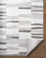 Close up of the Ananya Area Rug. Contemporary design in ivory, light brown, medium gray, peach, and taupe. Fold