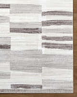 Close-up of the Ananya Area Rug, showcasing its ivory, light brown, and gray contemporary block pattern and textured weave. Corner