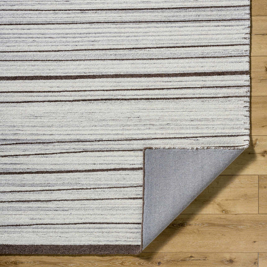 Close-up of the hand-tufted Cliona Area Rug. Features charcoal, ivory, and taupe stripes. 100% wool texture. Fold