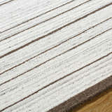 Close-up of the hand-tufted Cliona Area Rug, featuring a striped pattern in charcoal, ivory, and taupe wool. Texture