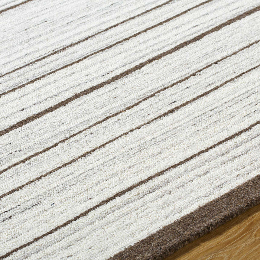Close-up of the hand-tufted Cliona Area Rug, featuring a striped pattern in charcoal, ivory, and taupe wool. Texture