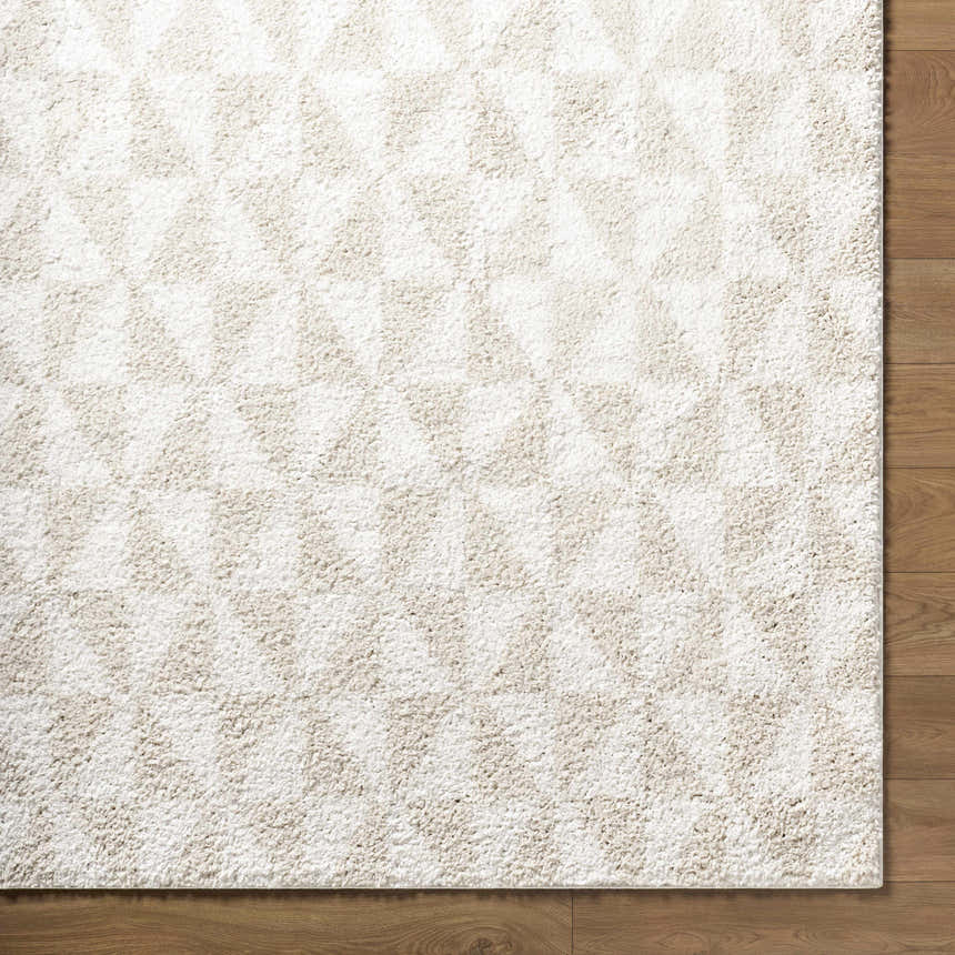 Close up of the Ceylan Area Rug, a shag rug with a geometric triangle pattern in medium gray and white. Corner