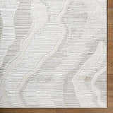 Close-up of the Aniela Area Rug. Contemporary design with cream, ivory, and gray tones. Textured, machine-woven rug. Corner