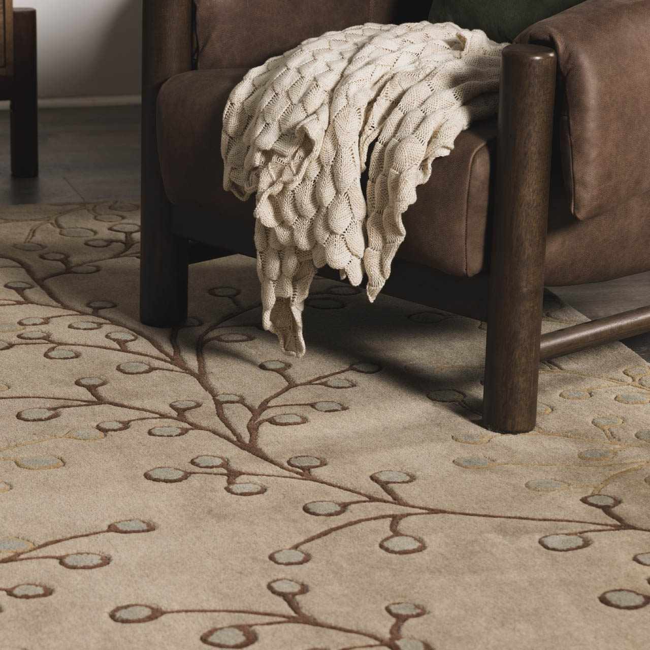 Living room scene with brown leather chair and Elsu Beige&Gray Wool Rug featuring a brown floral branch pattern. Roomscene-Rectangle