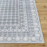 Close-up of the Rainier Gray Washable Rug showing its farmhouse style, traditional pattern, and soft off-white, pale blue, and sage colors. Front