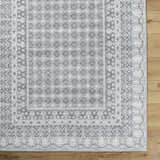 Close-up of the Rainier Gray Washable Rug. Farmhouse style rug with off-white, pale blue, sage, and tan traditional pattern. Swatch