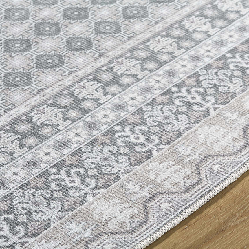 Close up of Rainier Gray Washable Rug showing farmhouse style pattern in off white, pale blue, sage, and tan colors. Texture