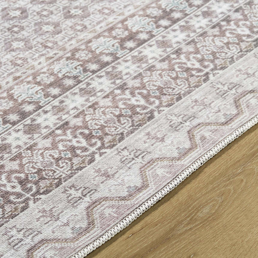Close-up of the Rainier Brown Washable Rug showing its traditional, farmhouse pattern and brown, gray, and sage colors. Texture