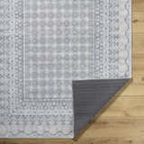 Close-up of Rainier Blue Washable Rug showing farmhouse style pattern and non-slip backing on a wood floor. Fold