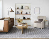 Living room scene with Rainier Blue Washable Rug, brown leather sofa, beige armchair, and light wood coffee table. Roomscene-Rectangle