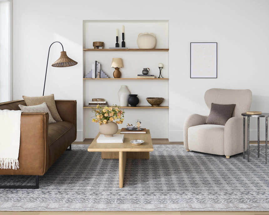 Living room scene with Rainier Blue Washable Rug, brown leather sofa, beige armchair, and light wood coffee table. Roomscene-Rectangle