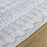 Close-up of the Rainier Blue Washable Rug showing its traditional pattern, pale blue, olive, and white colors, and woven texture. Texture