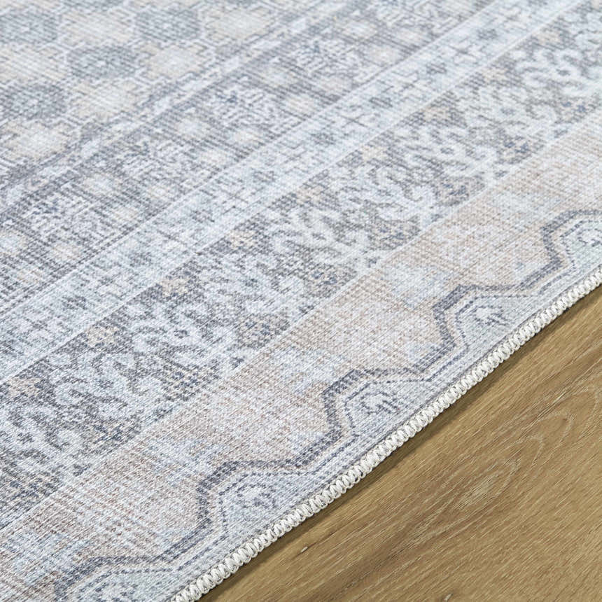 Close-up of the Rainier Blue Washable Rug showing its traditional pattern, pale blue, olive, and white colors, and woven texture. Texture