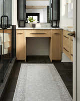 Bathroom scene with a Rainier Cottage Border Beige Washable Rug, wood vanity, and dark herringbone tile floor. Roomscene-Runner