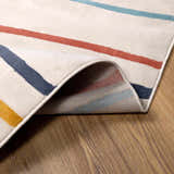 Close-up of New Southfields area rug showing its aqua, charcoal, mustard, and orange stripes on a cream background. Fold
