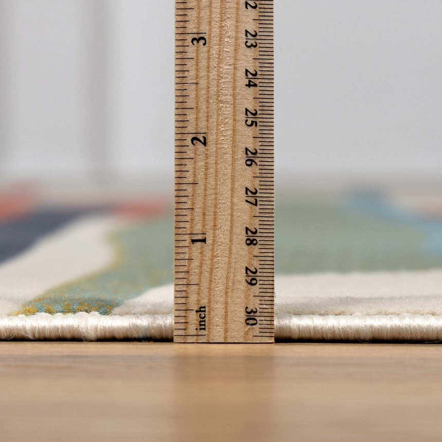 Close-up of the New Southfields Area Rug showing its thickness with a ruler. Abstract design with aqua, peach, and mustard hues. Pile