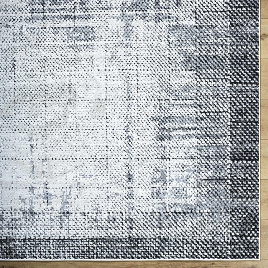 Close-up of the Colson Gray Area Rug, featuring a contemporary light silver, onyx, and silver gray pattern. Corner