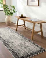 Hallway scene with a Colson Gray Area Rug, wood bench, vase with greenery, and hardwood floors. Roomscene-Runner