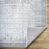 Close-up of Colson Sage area rug showing ash, silver gray, and slate blue contemporary pattern and machine woven texture. Fold
