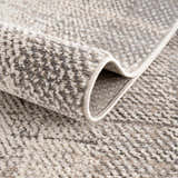 Close-up of the Colson Sage Area Rug showing its ash, silver gray, and pale pink textured weave. Fold
