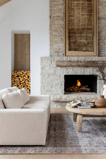 Living room scene with a beige sofa, stone fireplace, and the beige and gray Charla Washable Area Rug. Roomscene-Rectangle