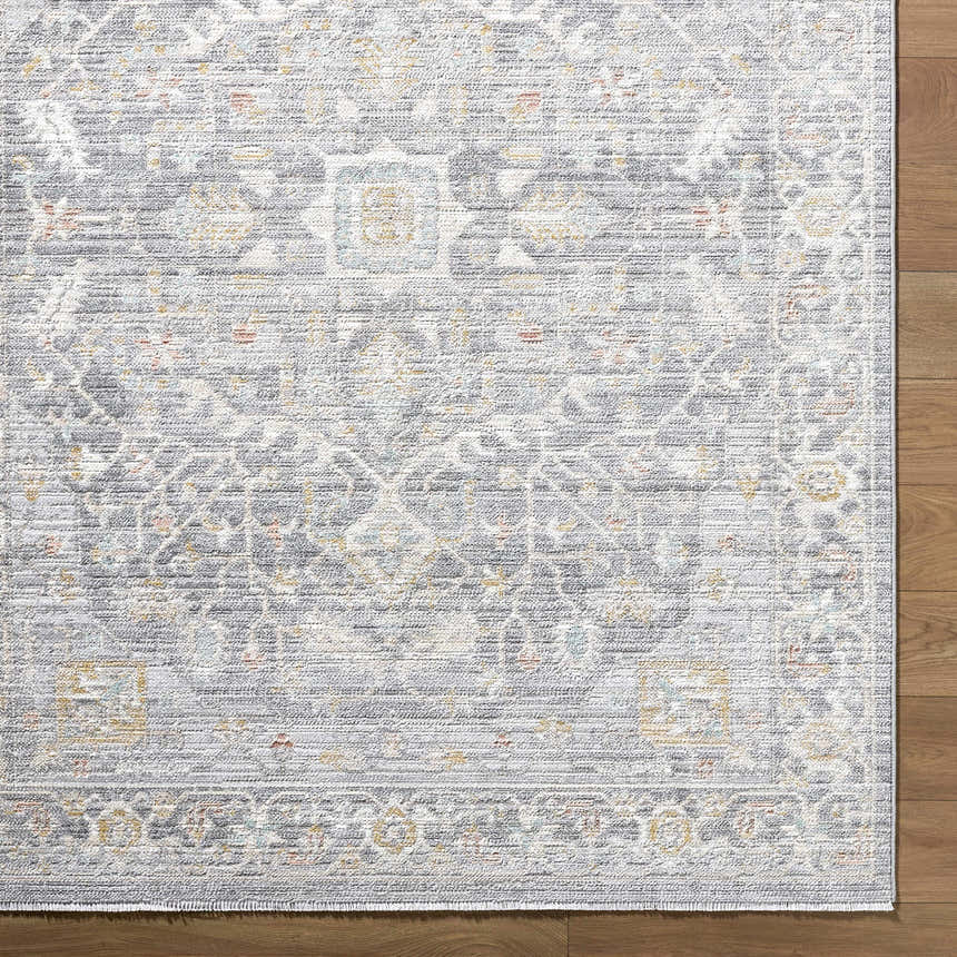 Close-up of the Xiye Silver Medallion Rug. Machine-woven polypropylene with a traditional medallion pattern in silver, gold, and blue. Corner