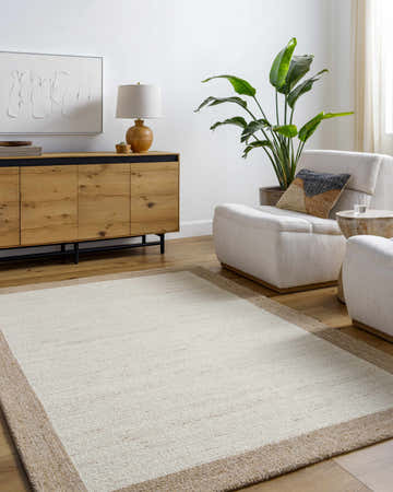 Living room scene with a beige Chasen Tufted Wool Area Rug, cream armchairs, and a wooden sideboard. Modern, neutral decor. Roomscene-Rectangle