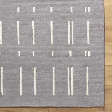 Close up of the Charan Slate Gray Area Rug. Gray wool rug with ivory vertical stripe pattern. Contemporary style. Corner