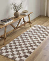 Hallway scene with a Canika Brown Washable Checkered Area Rug, wood bench, vase, books, and light wood floors. Roomscene-Runner