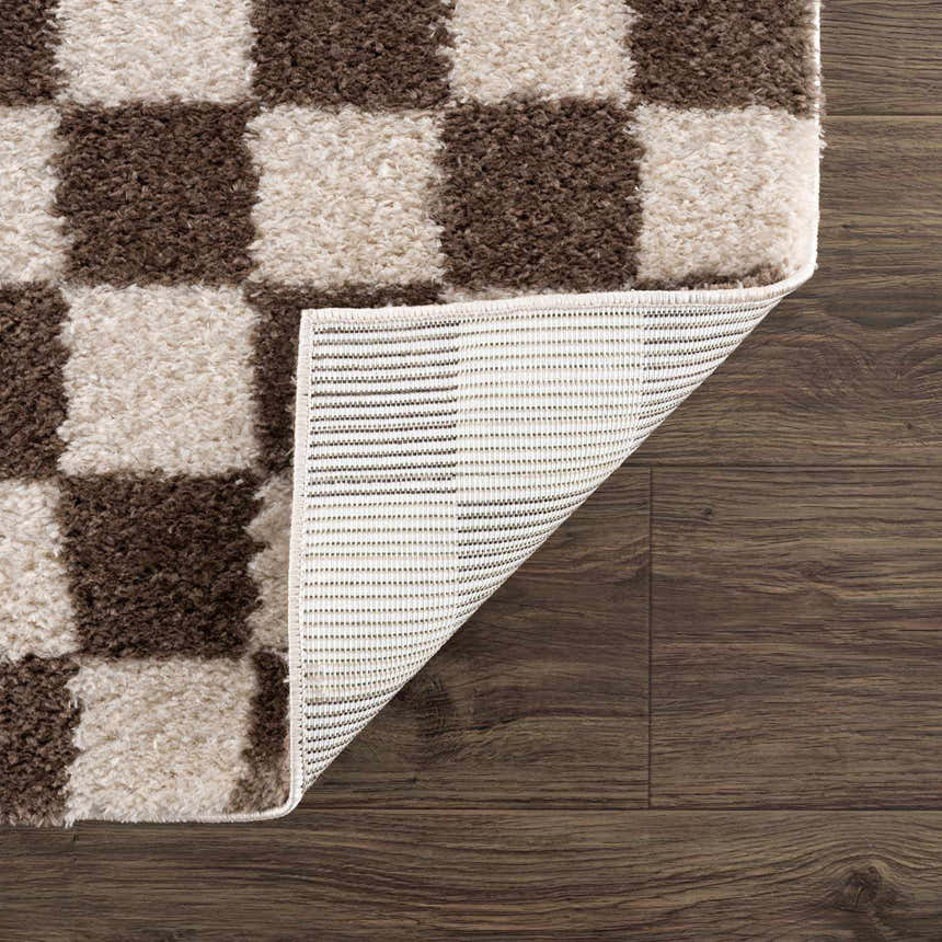 Close-up of a Canika Brown Washable Checkered Area Rug showing dark brown and peach squares, plus rug backing. Fold