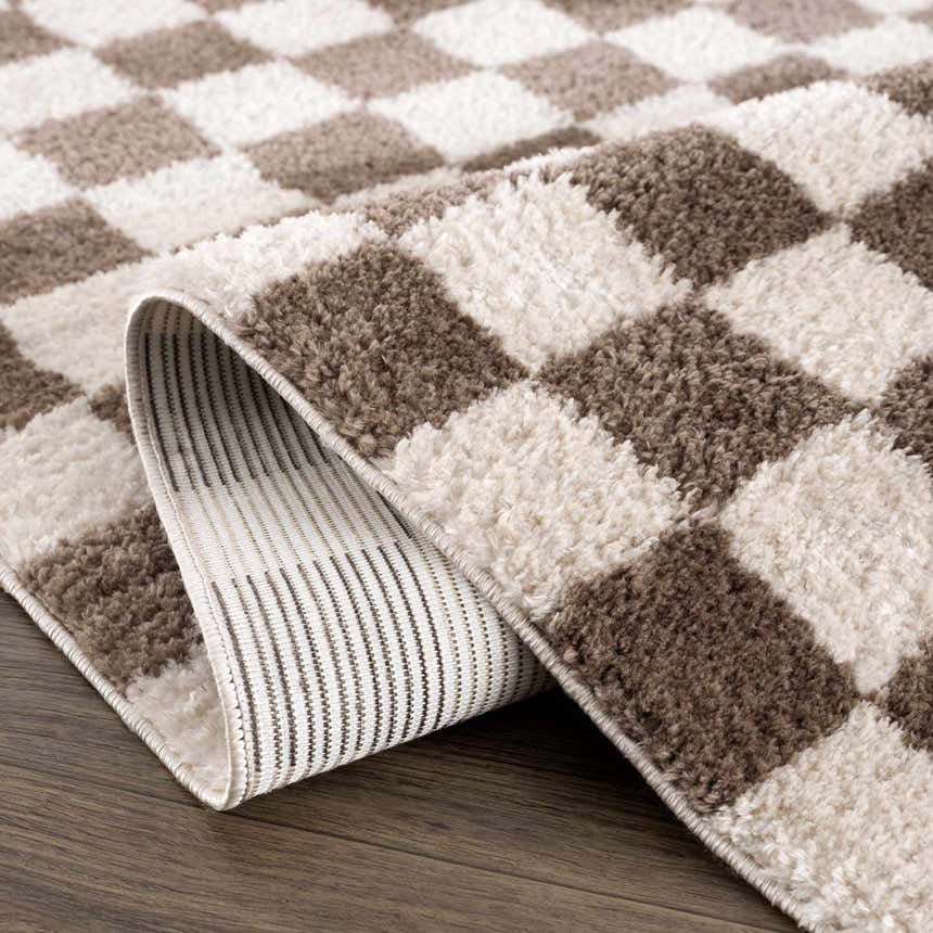 Close-up of the Canika Brown Washable Checkered Area Rug, showing dark brown and peach squares and the rug's backing. Fold