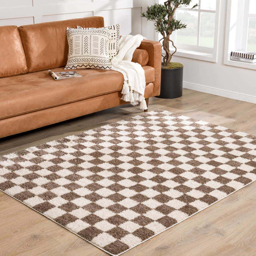 Living room scene with a Canika Brown Washable Checkered Area Rug, brown leather sofa, and light wood floors. Roomscene-Rectangle
