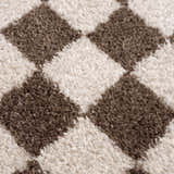 Close-up of the Canika Brown Washable Checkered Area Rug, showing its dark brown and peach diamond pattern and soft, textured weave. Texture