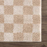 Close-up of Canika Checkered Cream Washable Area Rug. Beige and peach checkerboard pattern, soft polyester texture. Swatch
