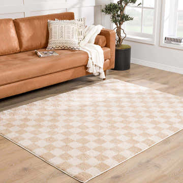 Living room scene with a Canika Checkered Cream Washable Area Rug, tan leather sofa, and light wood floors. Neutral tones. Roomscene-Rectangle