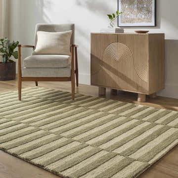 Living room scene with a gray chair and the Idaho Broken-Striped Green Area Rug on hardwood floors. Roomscene-Rectangle