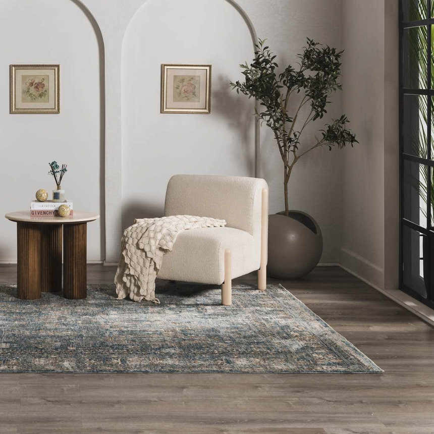 Living room scene with a Mirabel Denim Blue Traditional Rug, cream chair, and round side table. Roomscene-Rectangle