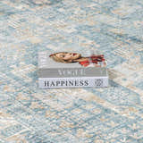 Close-up of the Mirabel Denim Blue Traditional Rug with a stack of fashion books on top. Styleshot
